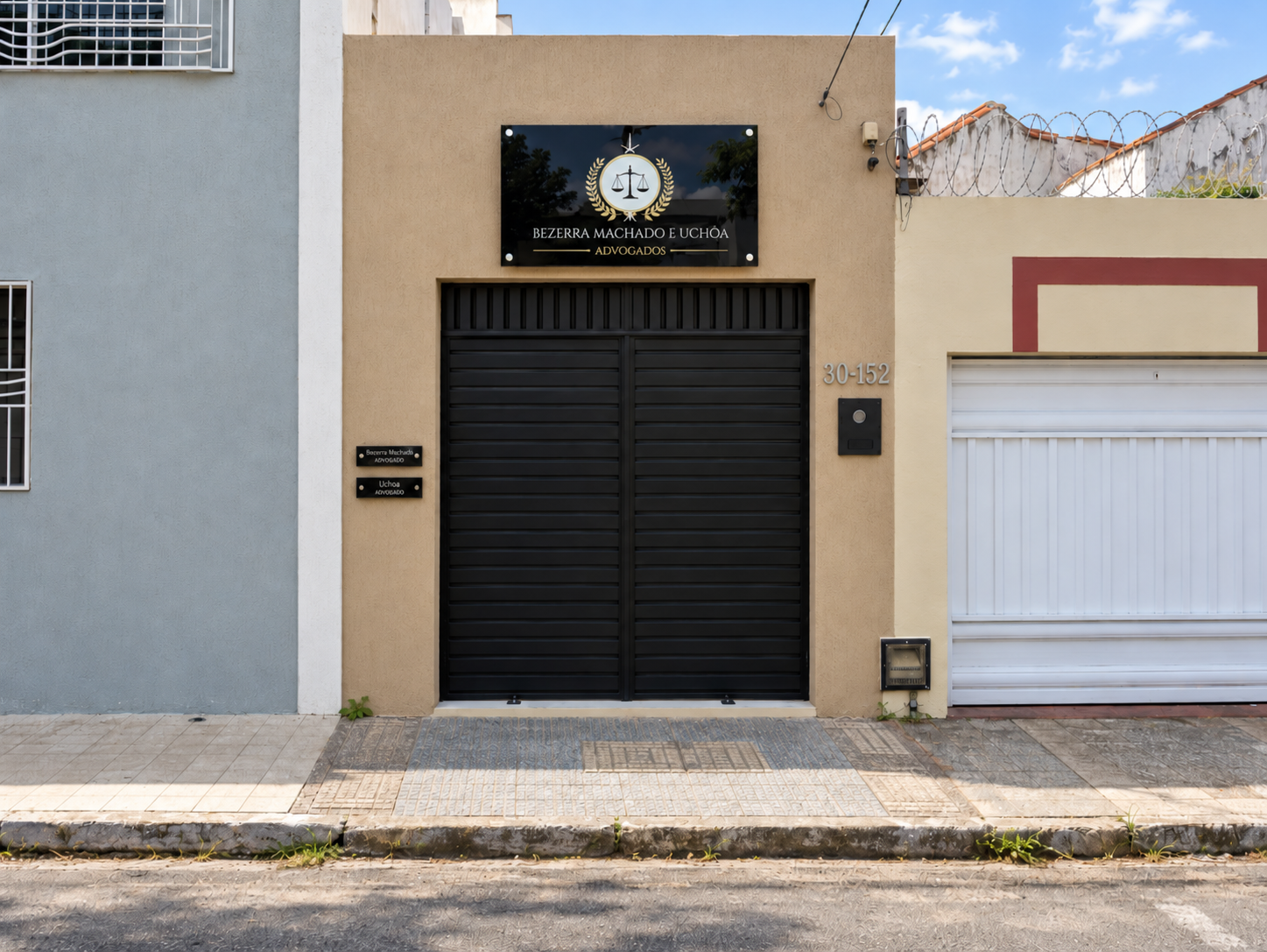 Fachada do escritório Bezerra Machado e Uchôa com placa preta e dourada e portão preto